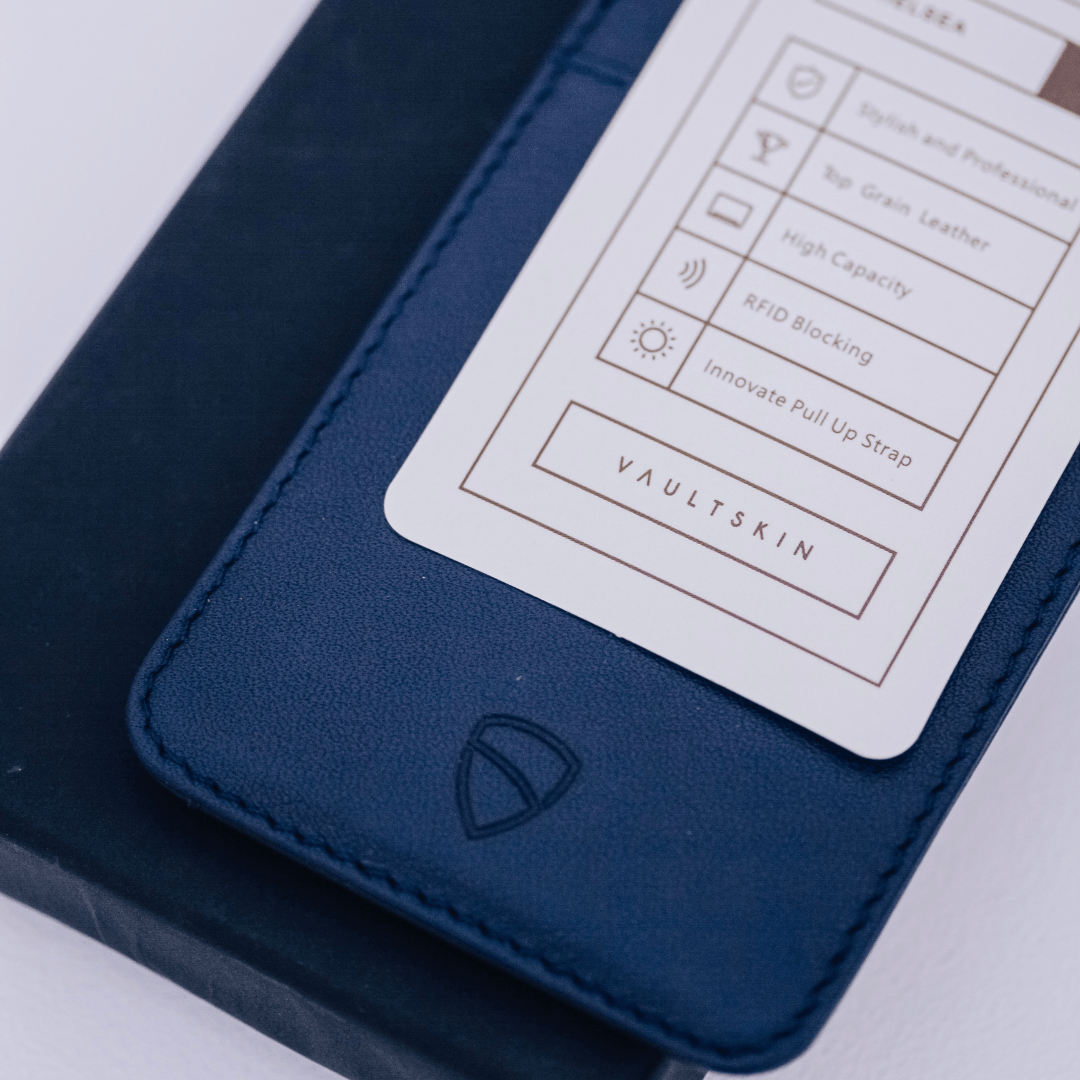 Navy leather CHELSEA card holder with a product feature card listing RFID blocking and top grain leather