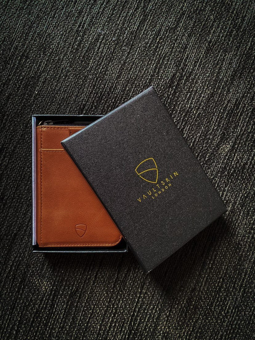Tan leather NOTTING HILL zip-around wallet in an open box beside its black branded packaging