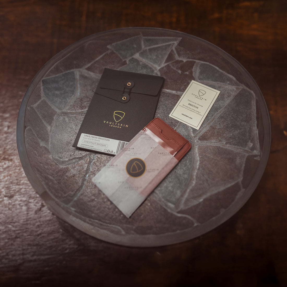 BRIXTON card holder with ID window beside its packaging box and a thank you card on a stone dish