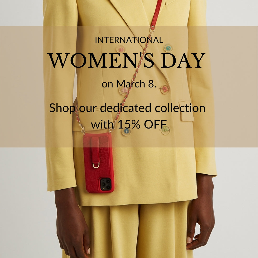 A woman in a yellow blazer wears a red leather phone case on a chain crossbody strap