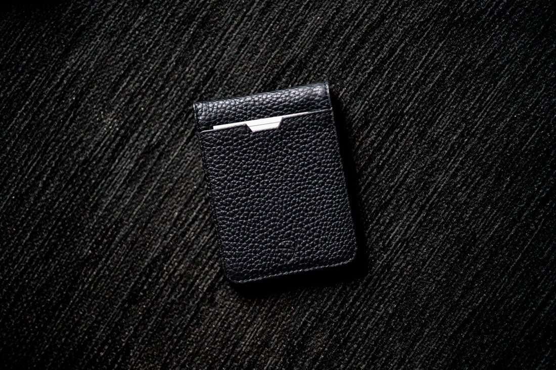 Black pebbled leather MANHATTAN bifold wallet with a card peeking from the slot