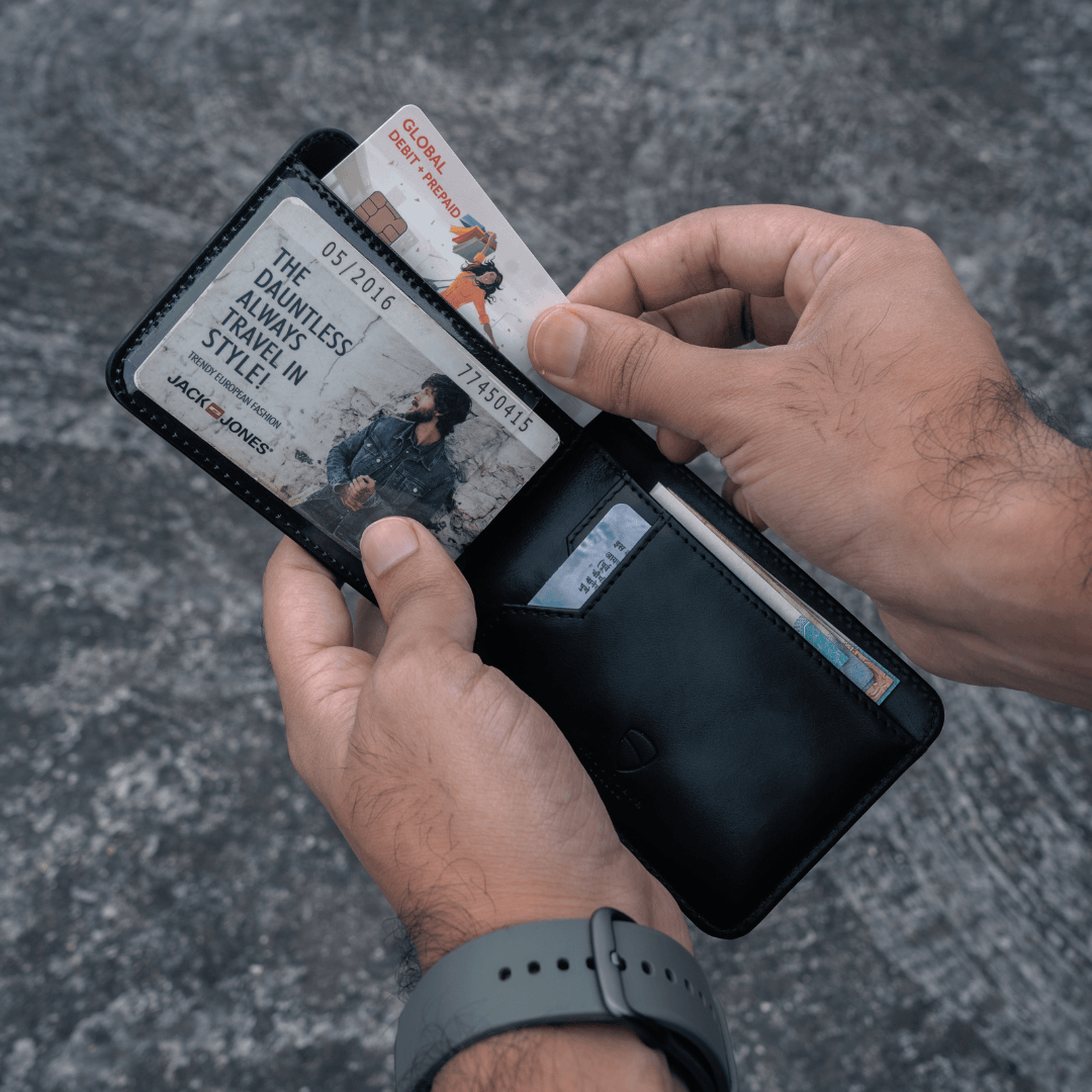 Two hands open a MANHATTAN bifold wallet with an ID card visible and another card being pulled out