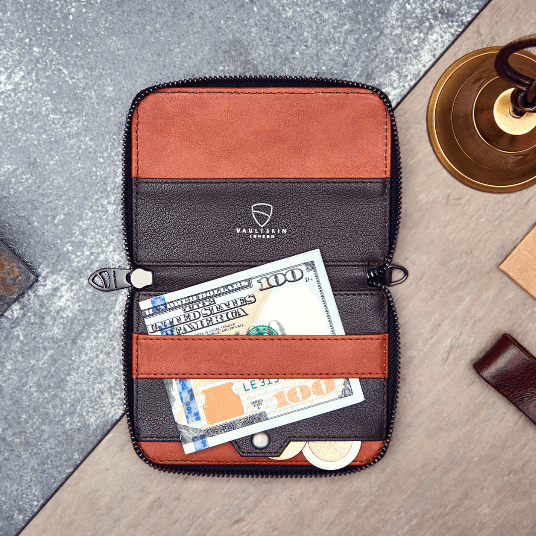 Open NOTTING HILL wallet with half-folded $100 banknotes and coins tucked in the coin pocket