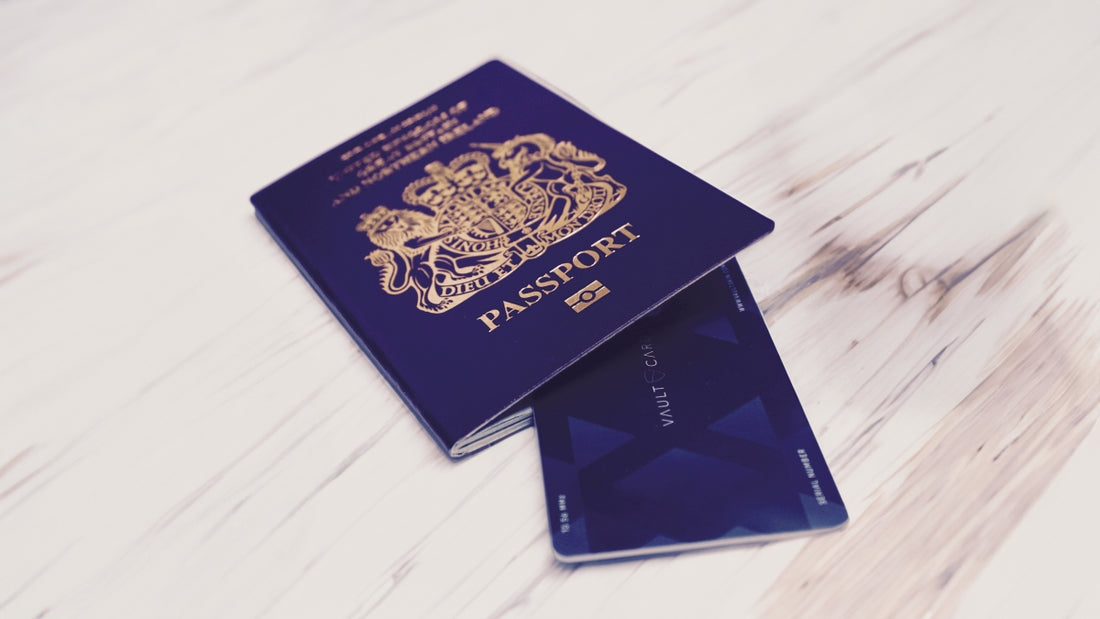 A VAULTCARD slim RFID-blocking card rests tucked inside a dark blue UK passport on a wooden surface