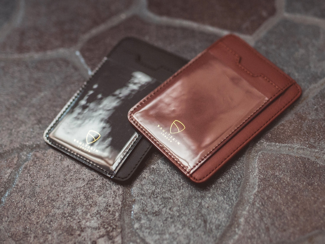 Black and brown BRIXTON card holders with ID windows lie side by side on a stone surface