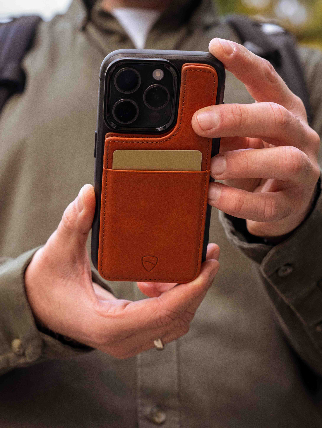 Hand holding a phone in a cognac ETON wallet case with 1 card tucked in the pocket
