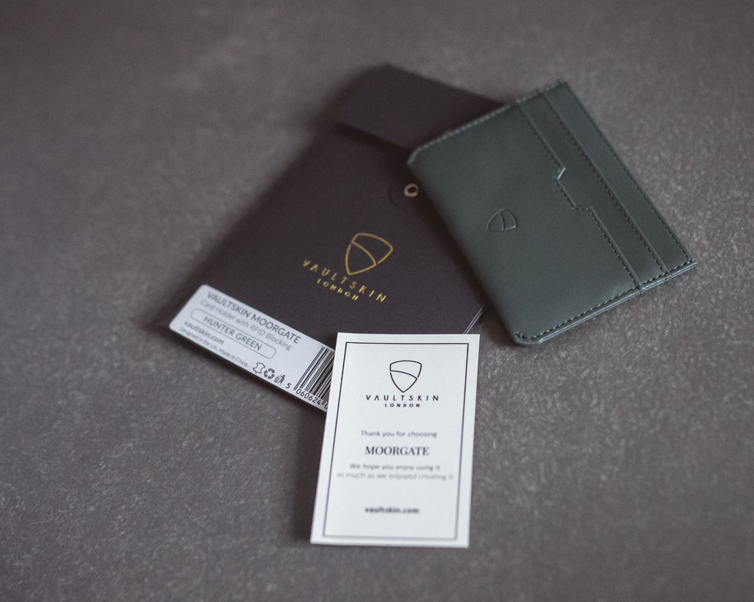 A green MOORGATE cardholder rests beside its packaging sleeve, product label and thank you card on a grey surface