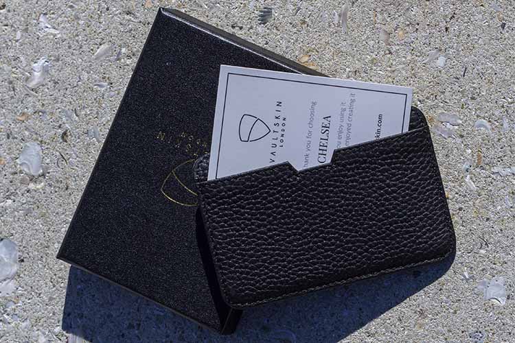 CHELSEA slim wallet in black pebbled leather resting on its open black box beside a thank you card