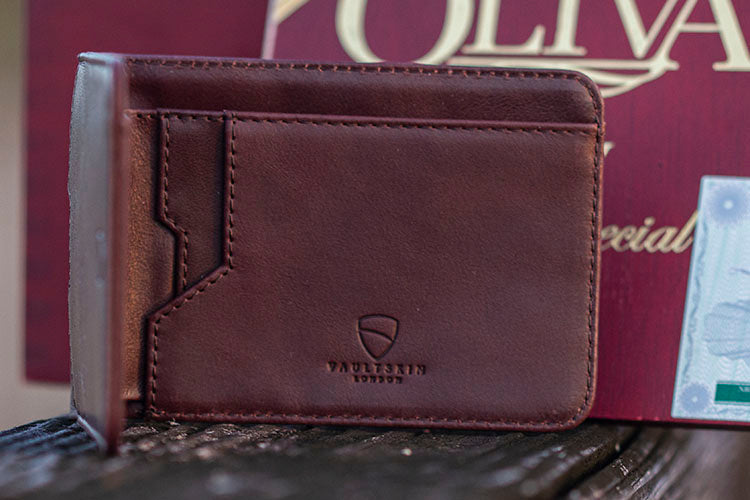 A MANHATTAN brown leather bifold wallet with visible card slots standing upright on a wooden surface