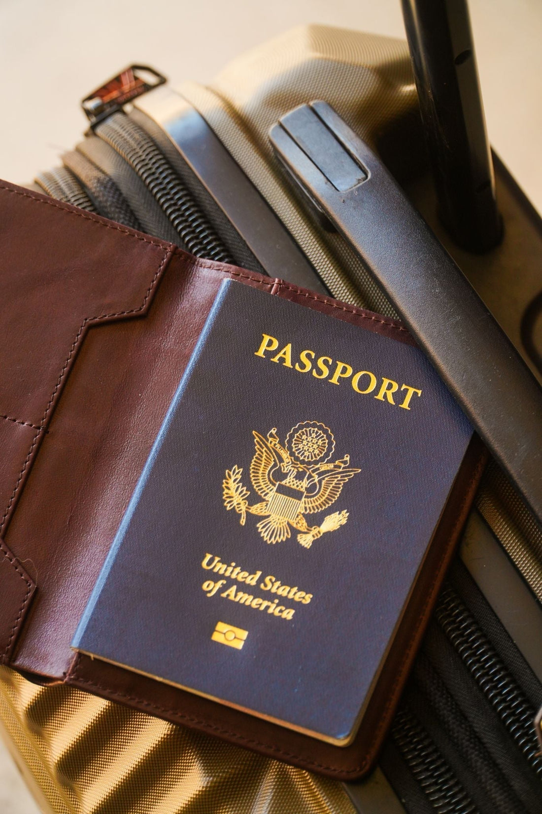 KENSINGTON passport wallet open to reveal a blue United States passport resting on top of luggage