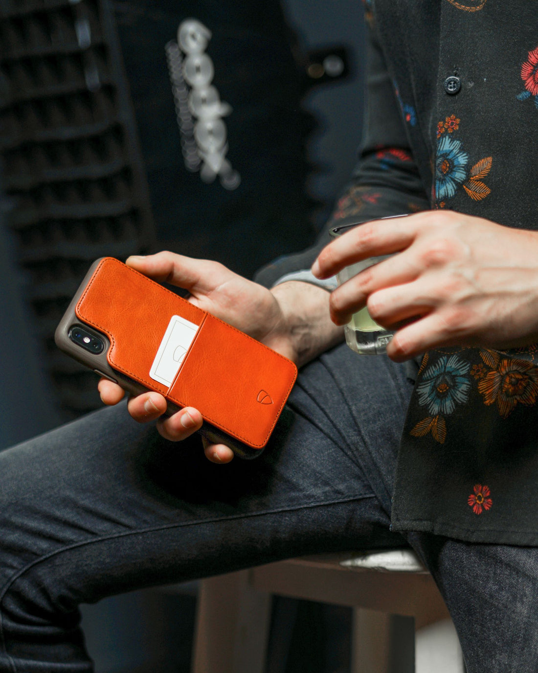 Hand holding an orange ETON ARMOUR phone case with a sliding card holder built into the back
