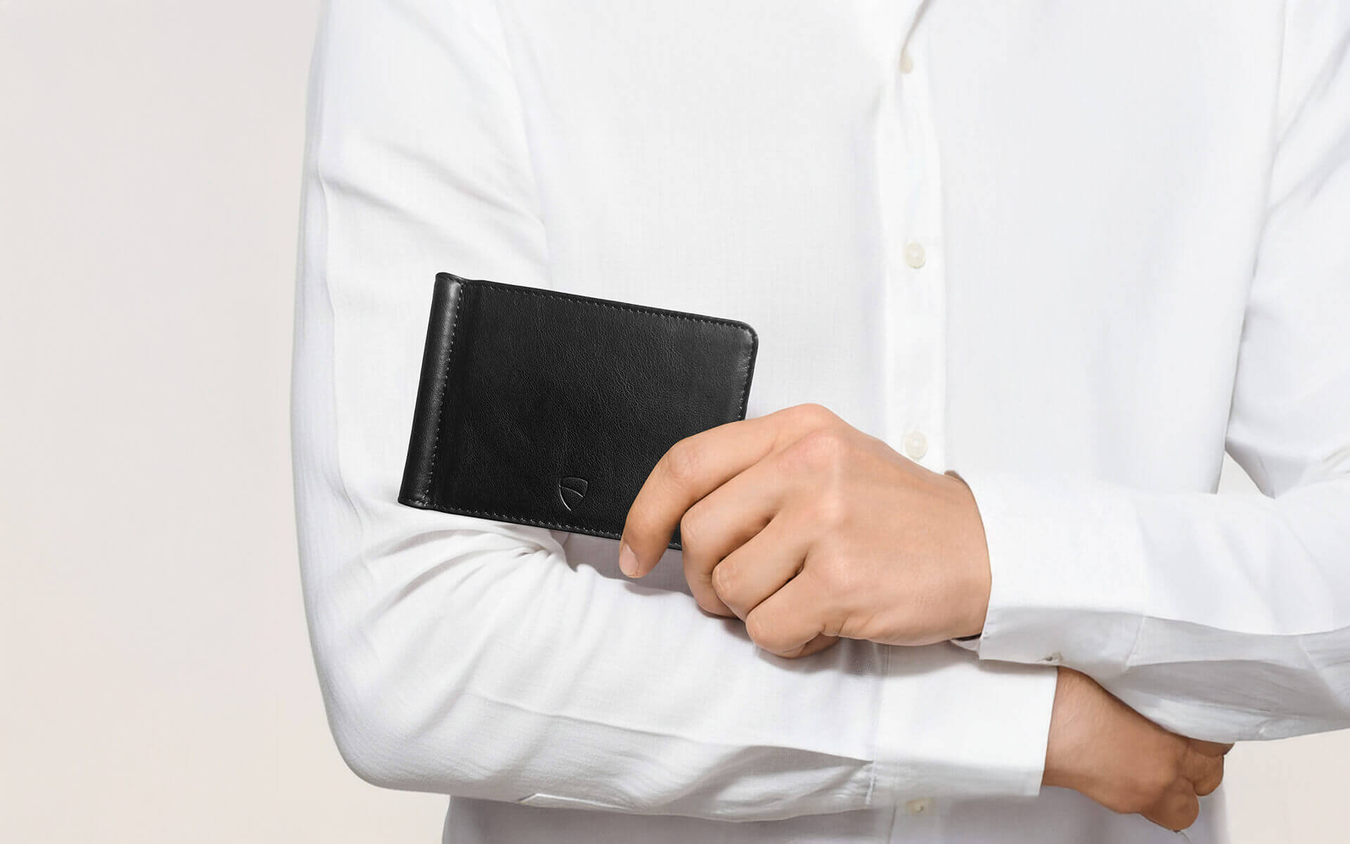Vaultskin BROMPTON black leather wallet held by man in white shirt, slim minimalist wallet with RFID protection