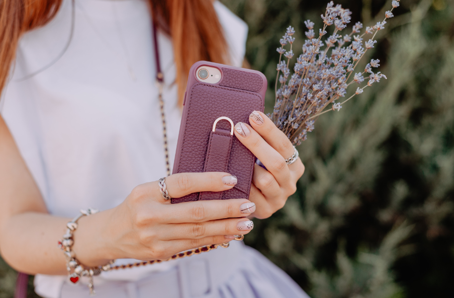 Woman in violet dress holding Vaultskin Victoria iPhone case in violet in her hands together with a small lavender bouquet