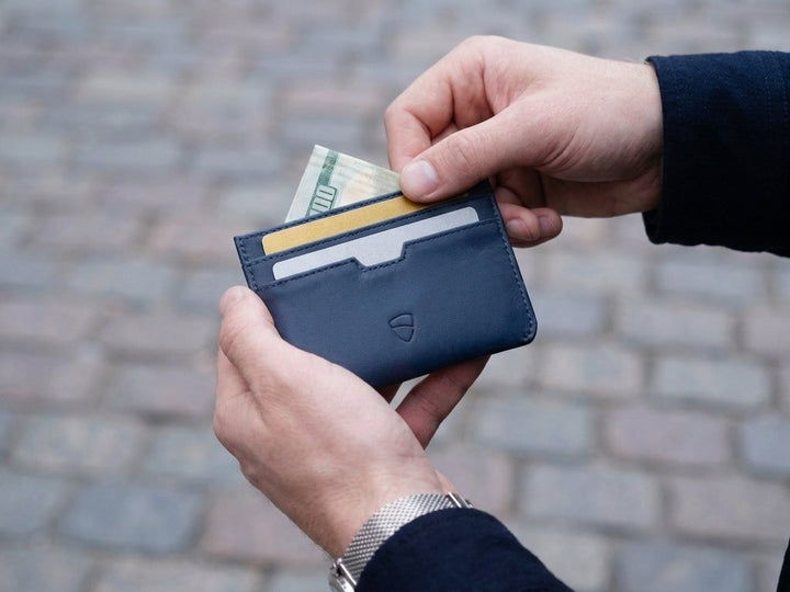 Vaultskin Moorgate minimalist leather cardholder in hand of the man with credit and debit cards and cash