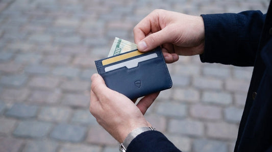 Vaultskin Moorgate minimalist leather cardholder in hand of the man with credit and debit cards and cash
