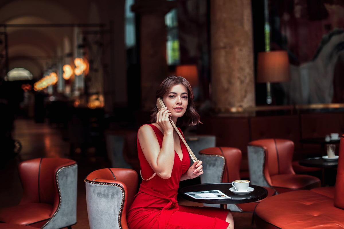 Woman in a red dress talking on her phone in a café